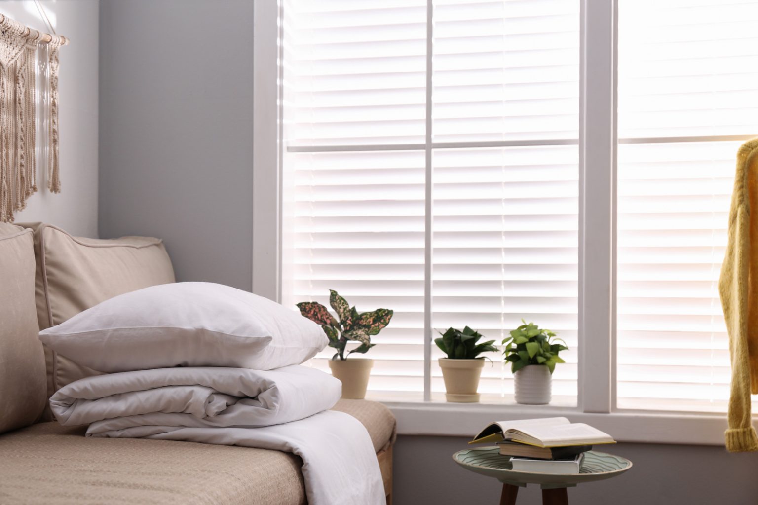 Living room sofa with throw near a window fitted with moisture-resistant PVC Venetian blinds