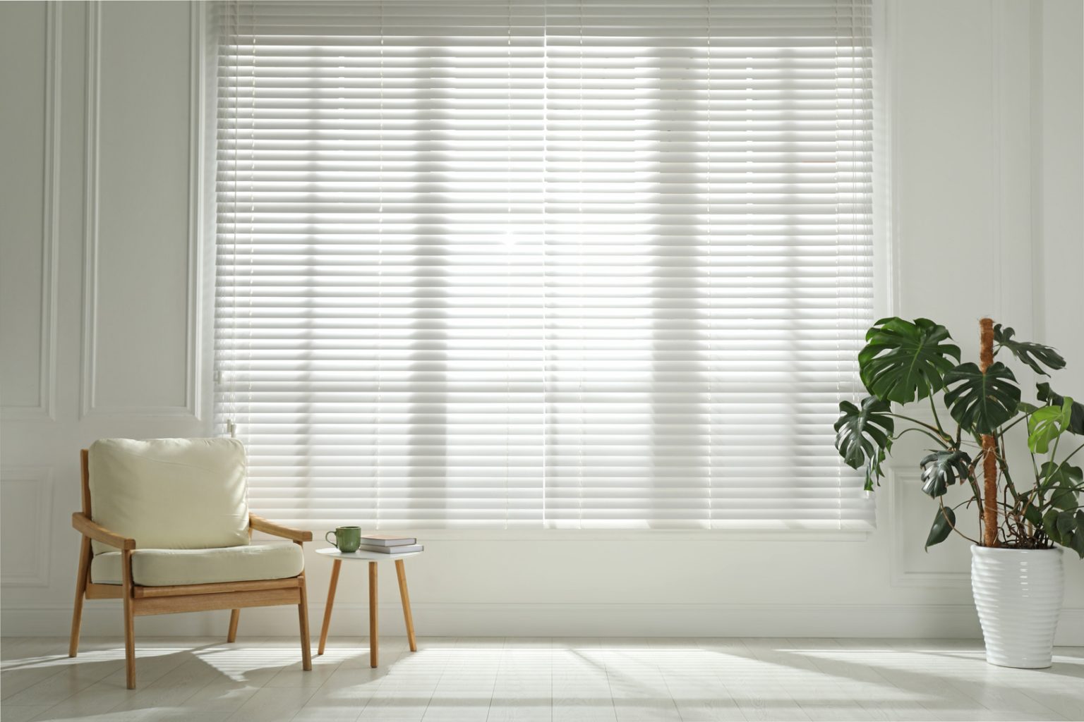Cosy armchair and houseplant beside a large window with easy-clean PVC Venetian blinds