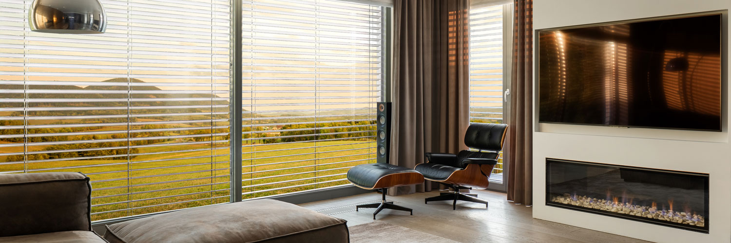A floor-to-ceiling windows covered by silver horizontal venetian blinds