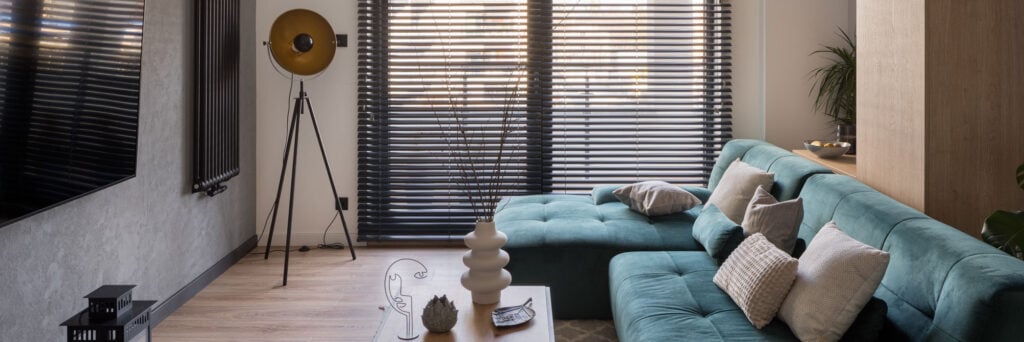 A dark horizontal venetian blinds covering a window that lets in soft afternoon light.