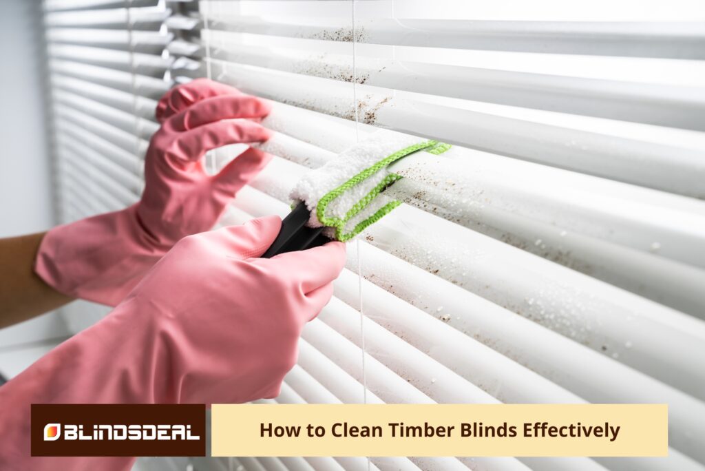 A close-up of hands in pink rubber gloves using a specialised microfiber slat-cleaning tool to wipe dirt from white venetian blinds