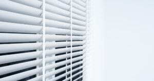 Close-up of white Venetian blinds with wide horizontal slats.