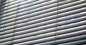 Close-up of thin, horizontal silver Venetian blinds with visible ladder cords.