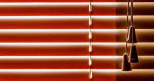 A close-up view of closed timber Venetian blinds in a warm orange-brown tone