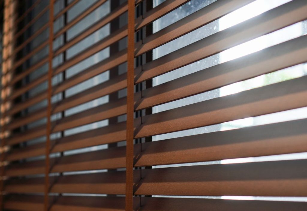 An angled, eye-level view of a set of brown wooden horizontal blinds.