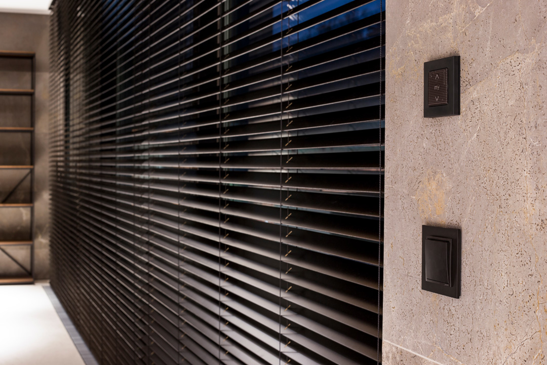 A close-up view of dark, motorised horizontal blinds in a modern interior