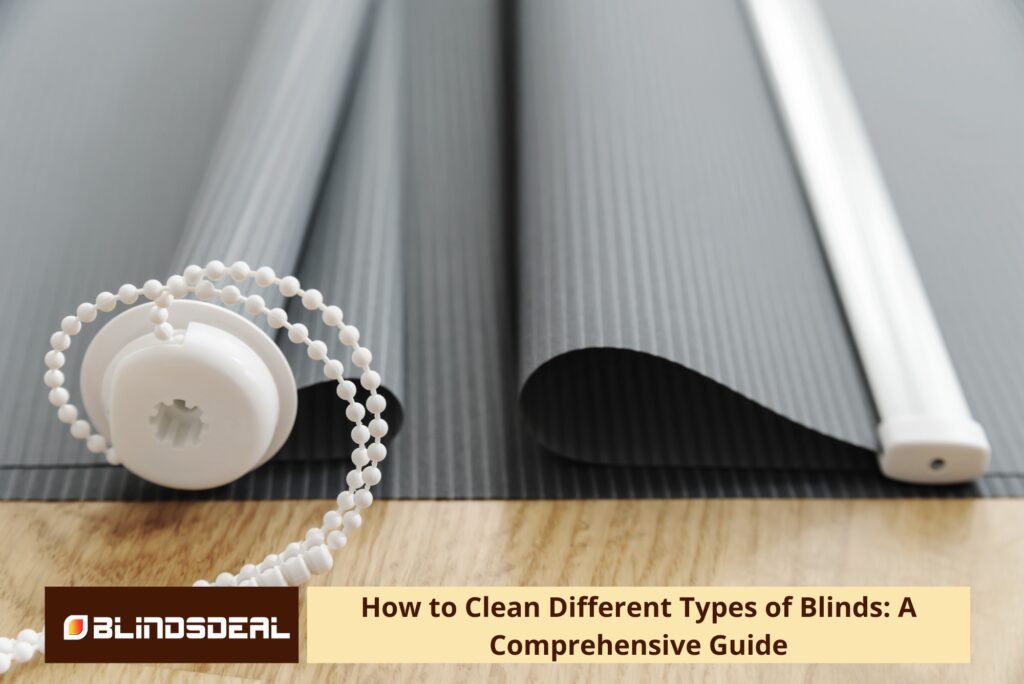 A close-up of dark grey roller blind fabric and a white beaded pull chain mechanism lying on a wooden surface