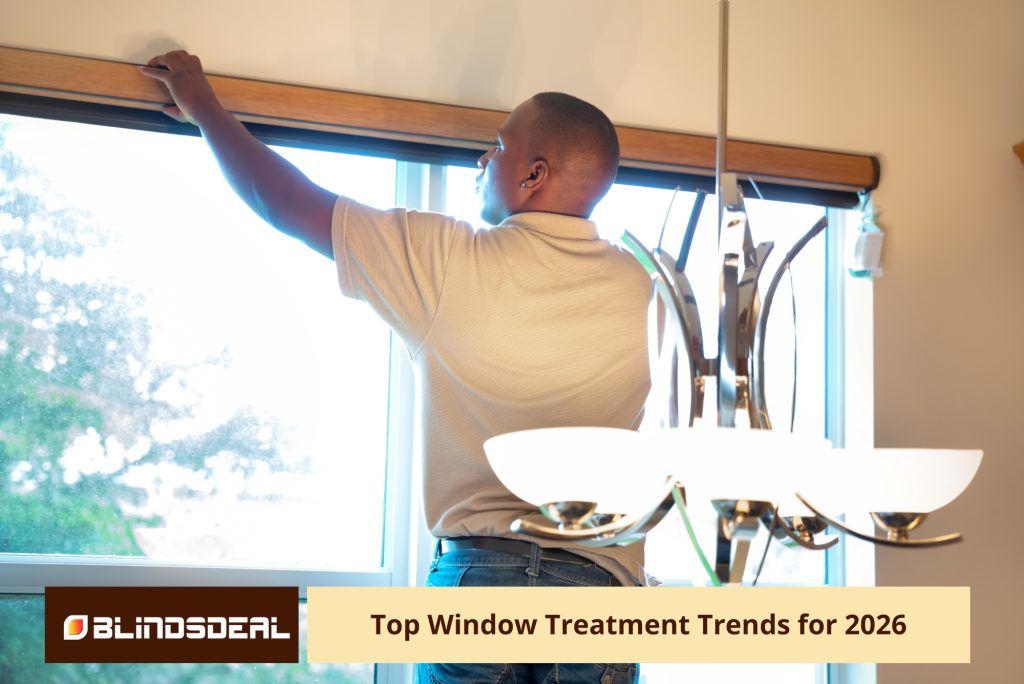 A man installs a wooden valance for a window shade in a bright room.