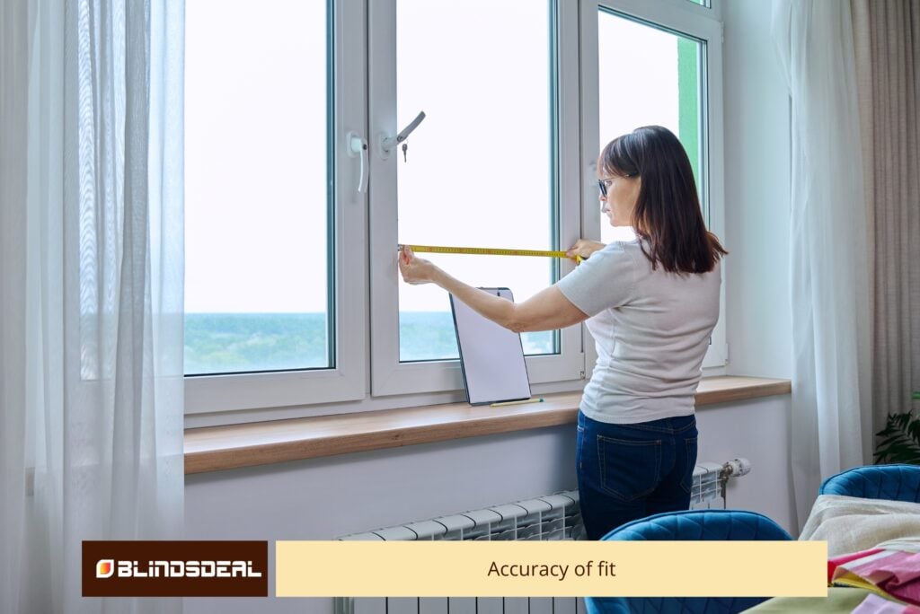 A woman uses a yellow tape measure to gauge the width of a white window frame for a custom blind fitting.