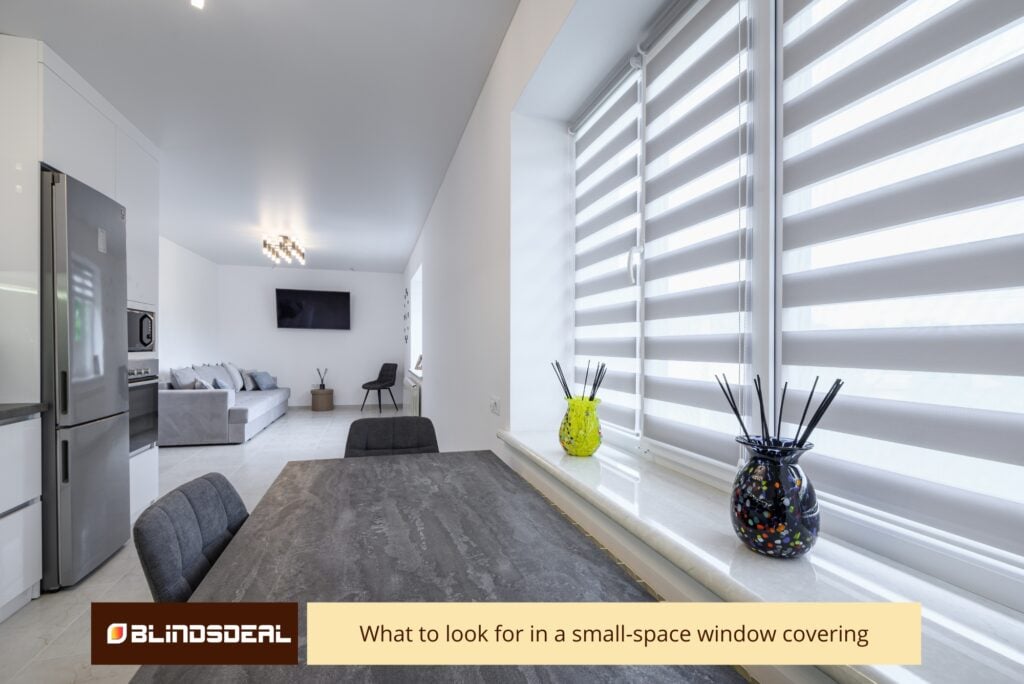 Modern open-plan apartment featuring white zebra-style roller blinds on a large window beside a dining table