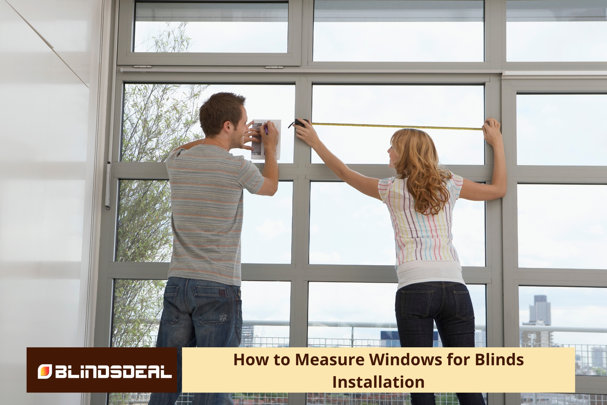 A man writing on notes while a woman uses a tape measure across a window frame