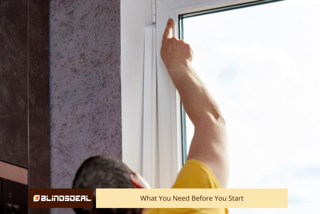 A person pointing at the top inner corner of a white window frame